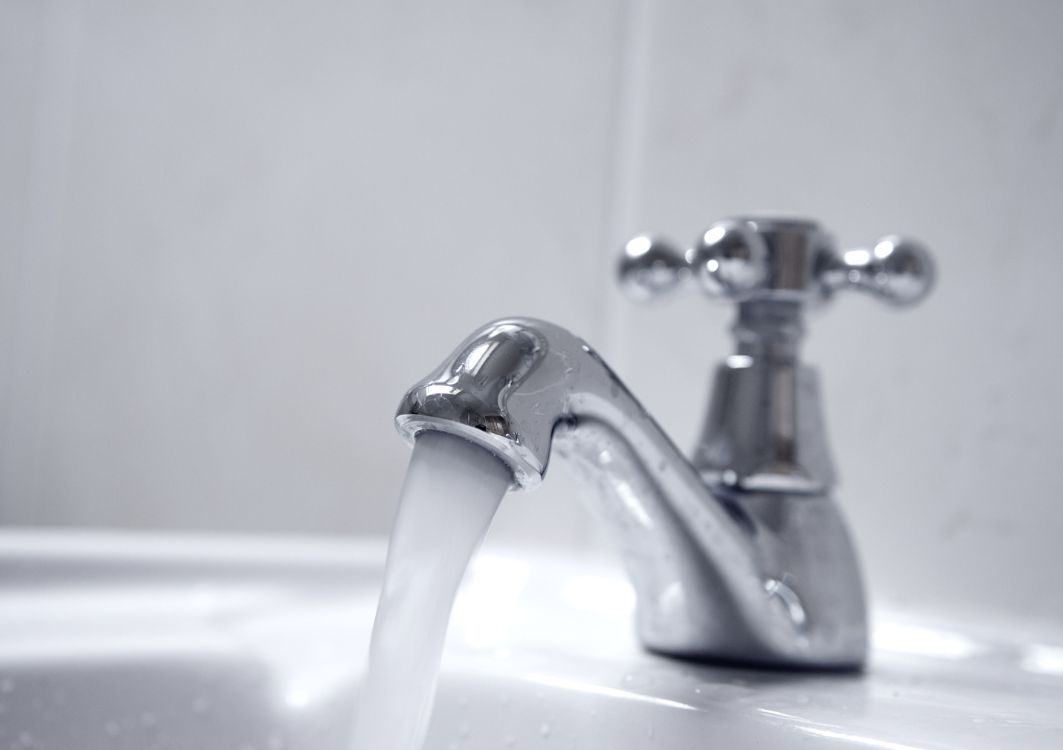 A silver faucet shines as water runs freely from it.